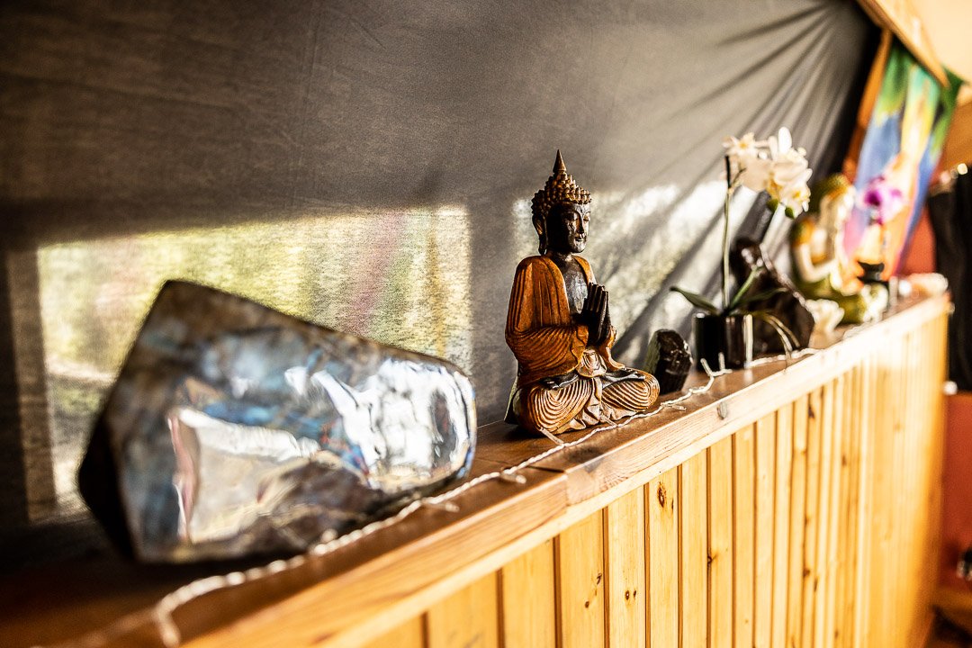 Figura de Buda, una piedra y flores sobre un estante de madera