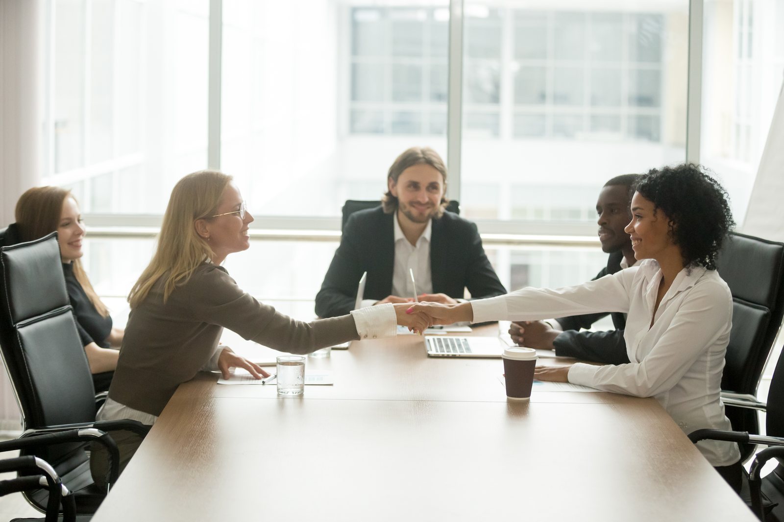 Dos personas se dan la mano en una mesa de reunión