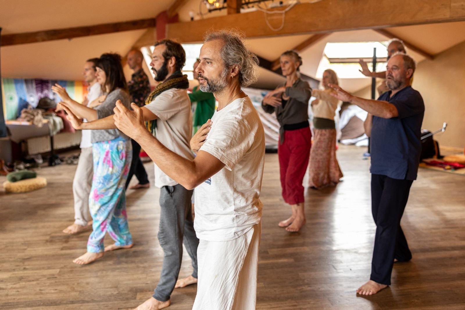 Grupo en movimiento durante una meditación activa, en una sala con techo de madera